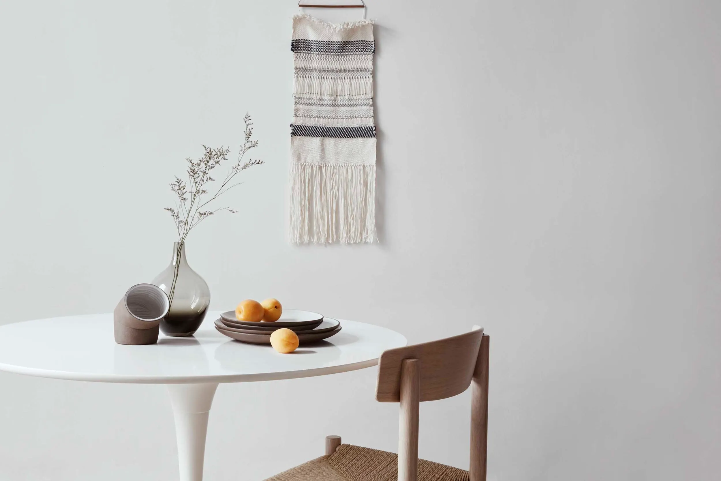 A bright dining nook with vases, plates and fruit on the table