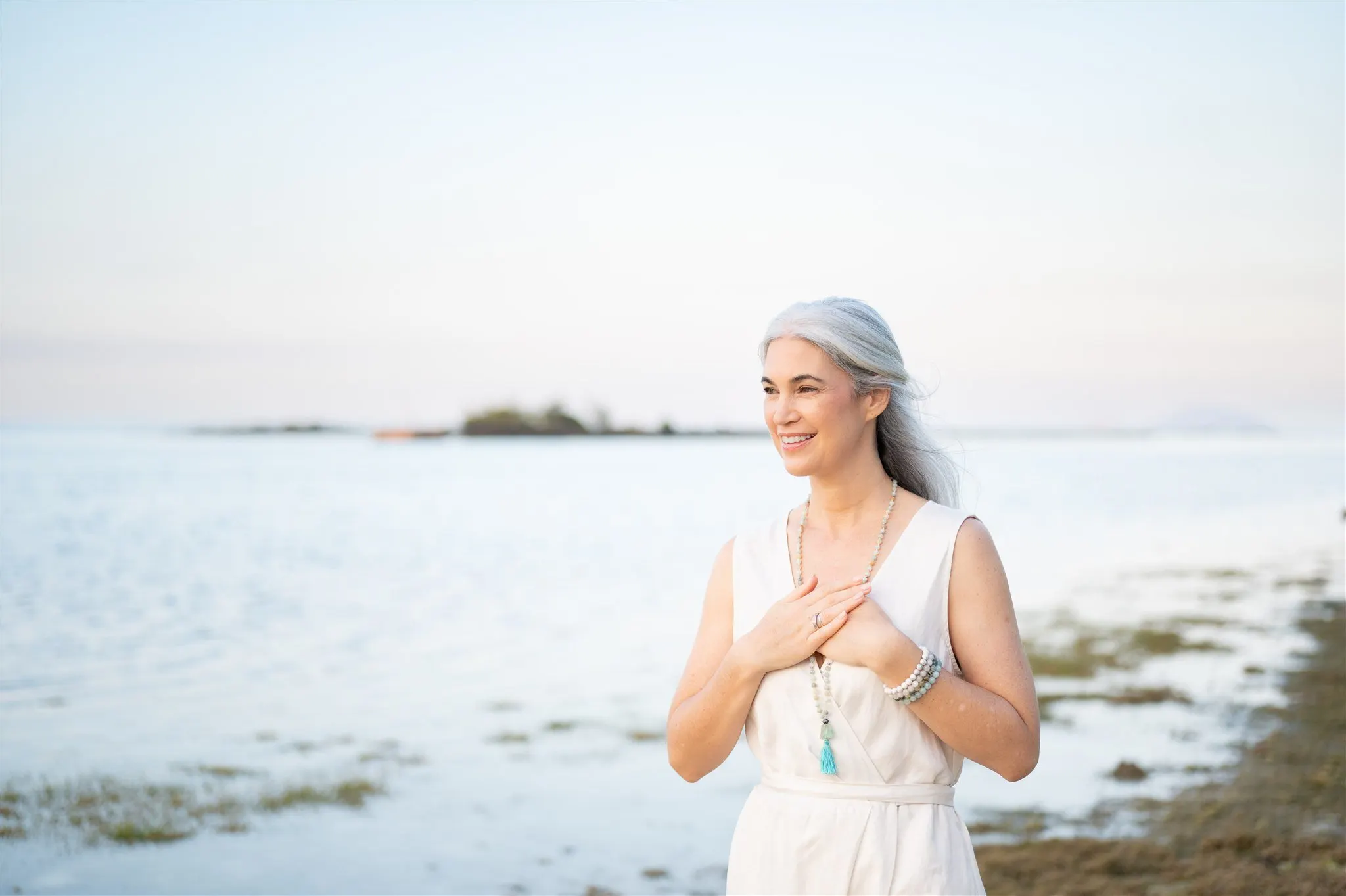 Stephanie standing at the shore at dusk, hands resting on her chest
